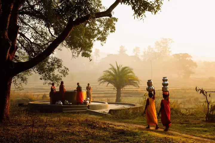 Women carrying water pots near a village well